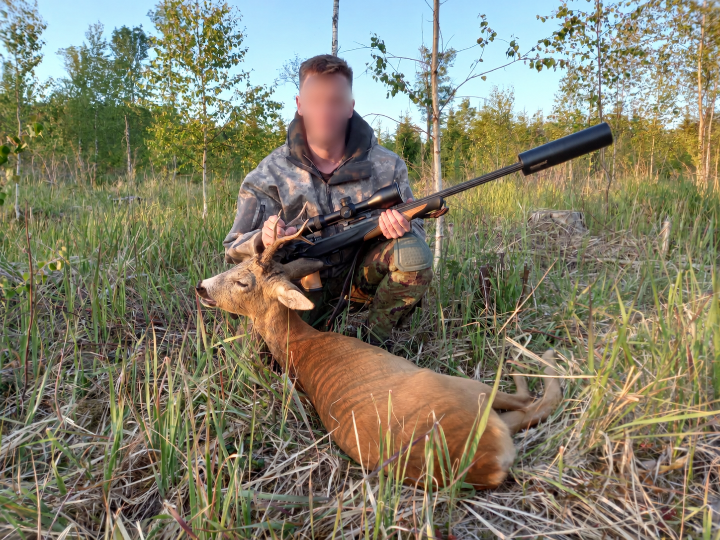 Hunter with a harvested roe deer in the forest